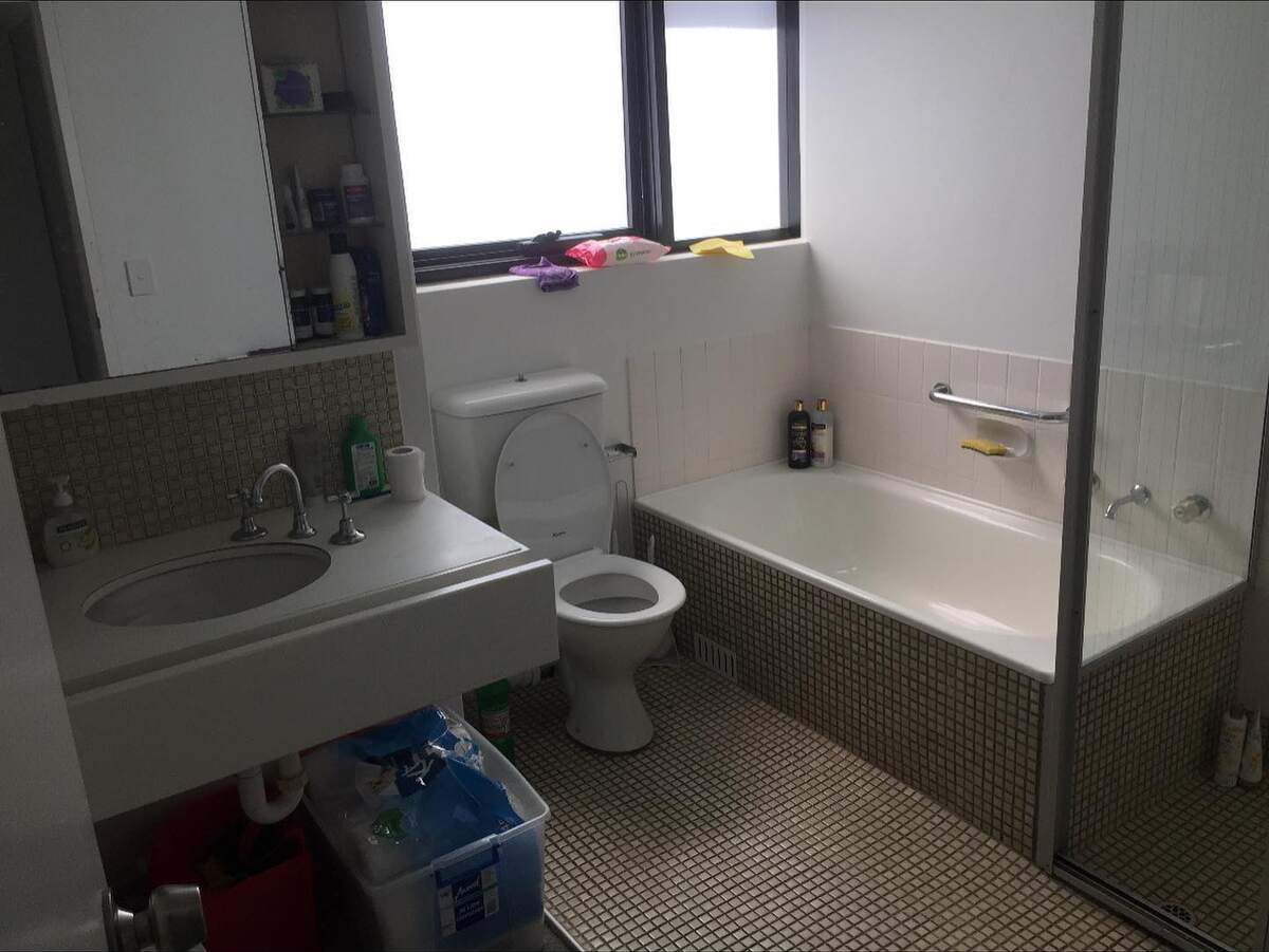 Dated bathroom in Manly before the strip-out, with bath, toilet, wall-hung basin and mosaic floor tiles